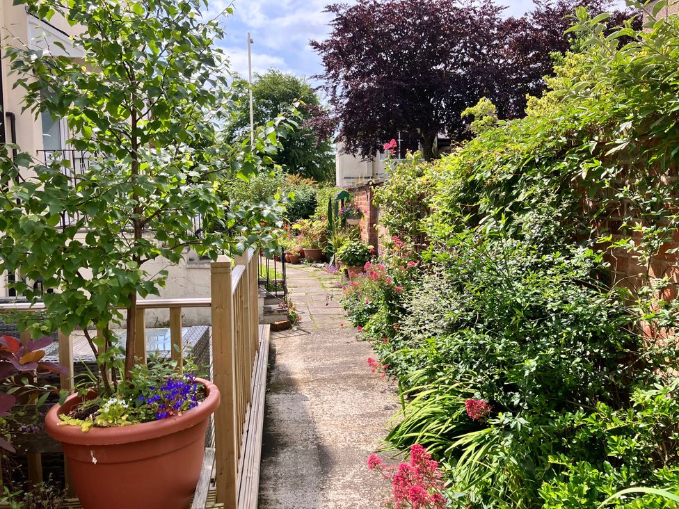 A garden pathway with flower beds and pots at Flat 2A