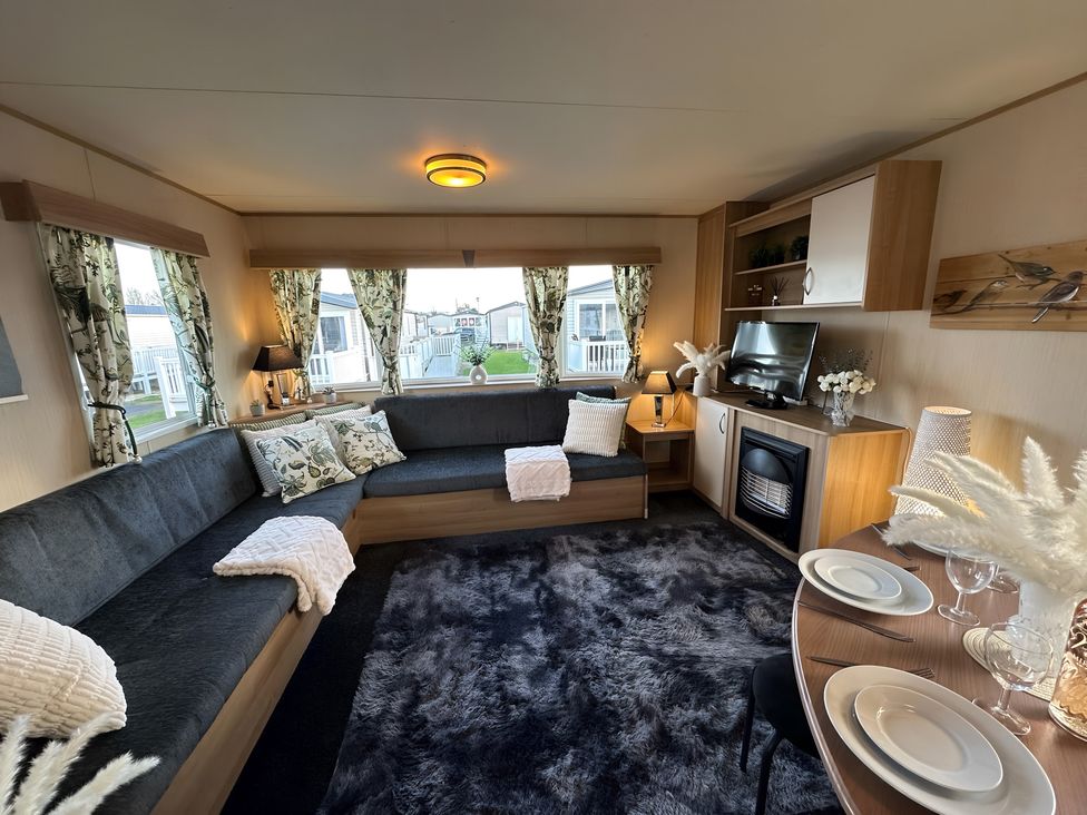 A living room with a sofa and dining area at a holiday home in a caravan park