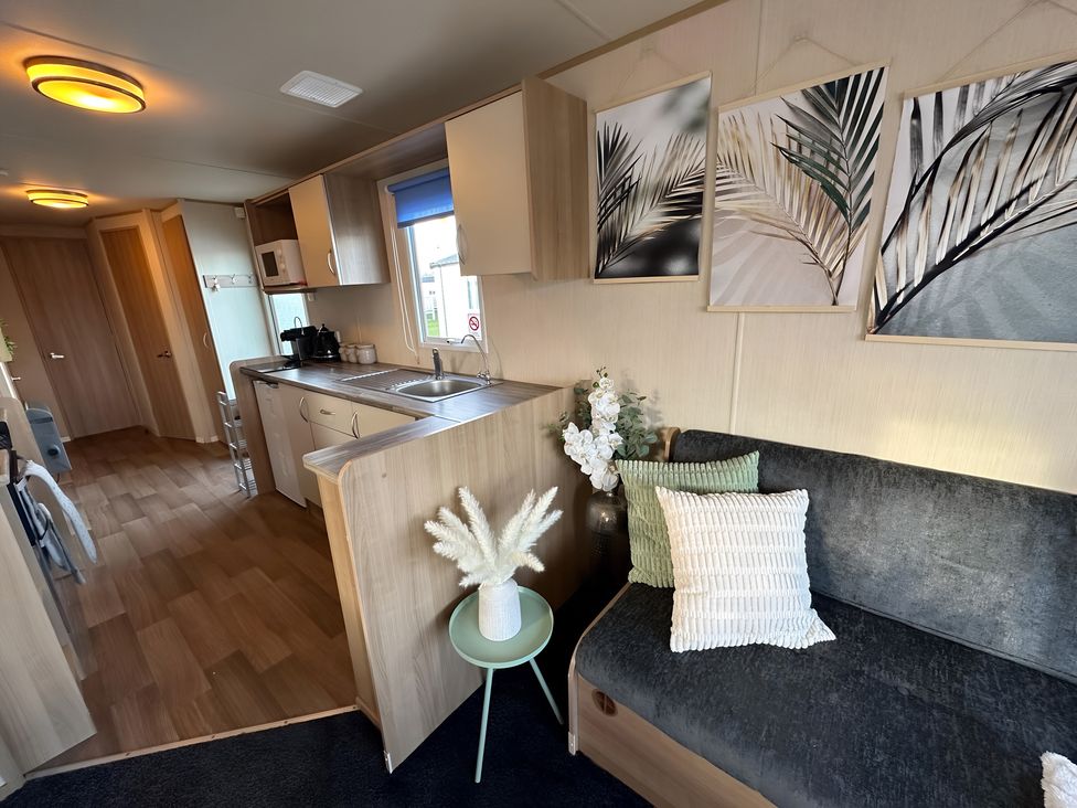 A living room with a kitchen area, sofa and decorative elements at the property