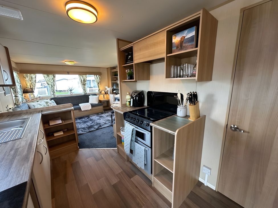 A kitchen with stove, sink, refrigerator and countertop in a modern setting
