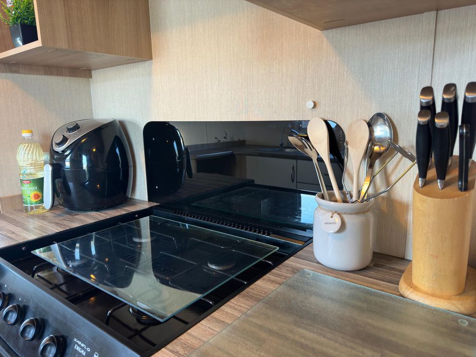 A kitchen countertop with a cooktop, utensils, and an air fryer at 