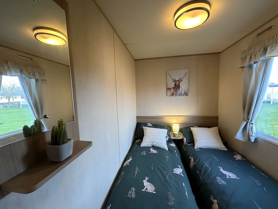 A bedroom with two beds and a mirror at a property in an outdoor setting