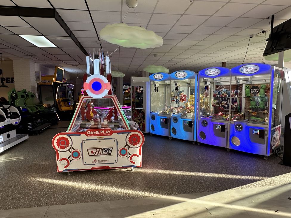 An arcade with claw machines and a game console in a fun space