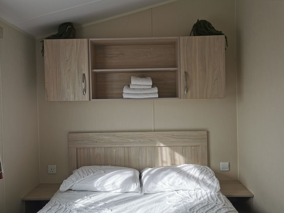 A bedroom with a bed and shelves holding towels at the property in 