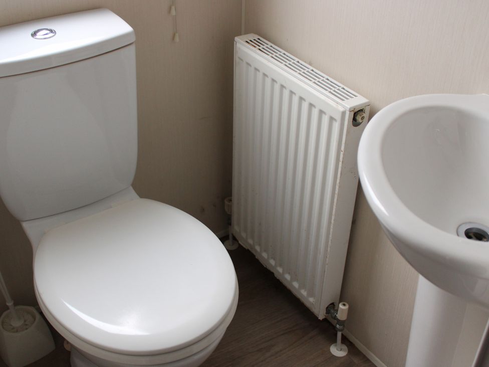 A bathroom with a toilet, hand basin, and radiator