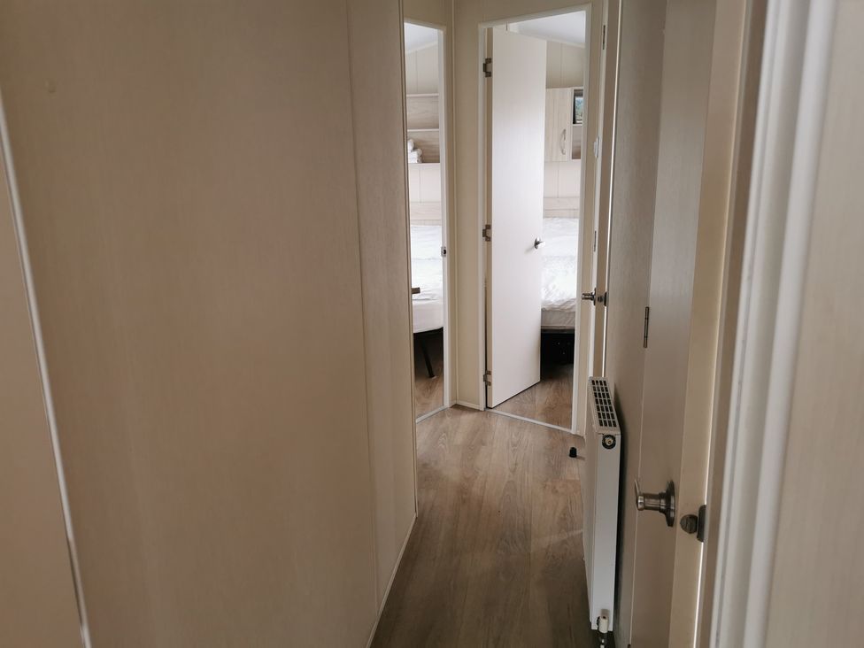A hallway with doors leading to a bedroom and a radiator at a property