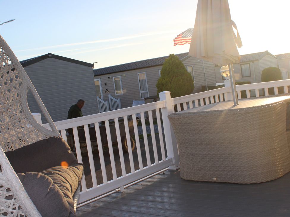 An outdoor seating area with a chair, table, and umbrella at a mobile home park