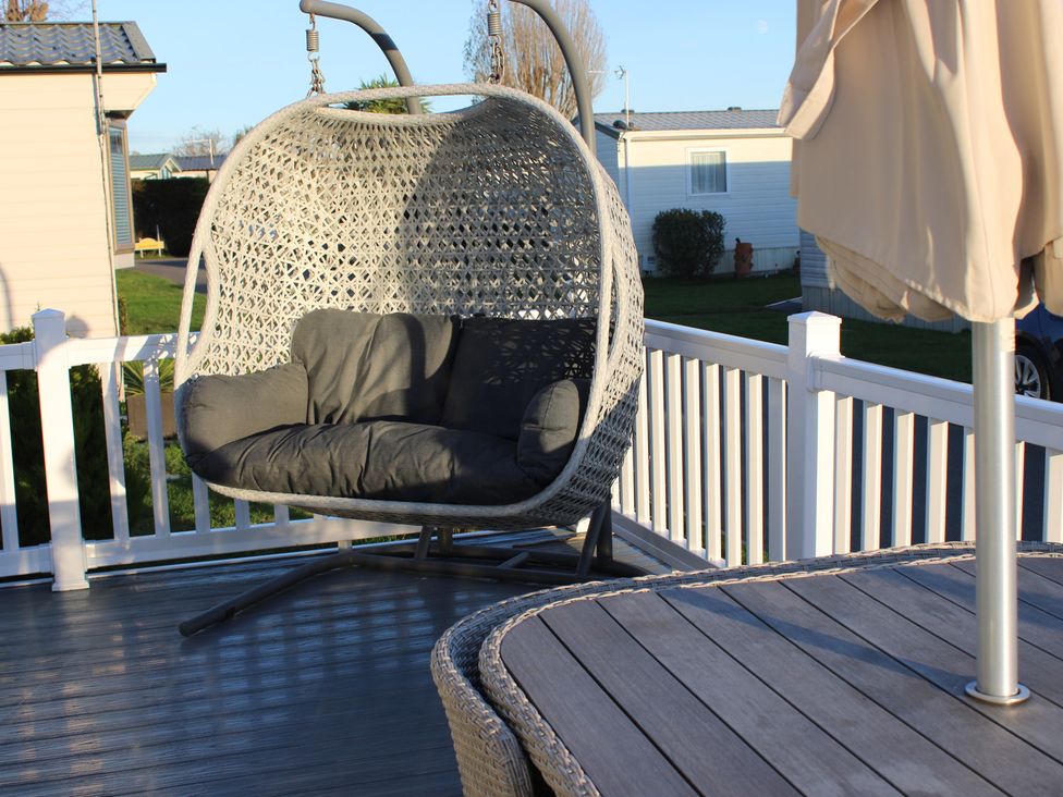 A hanging chair and table with umbrella on a deck in outdoor area