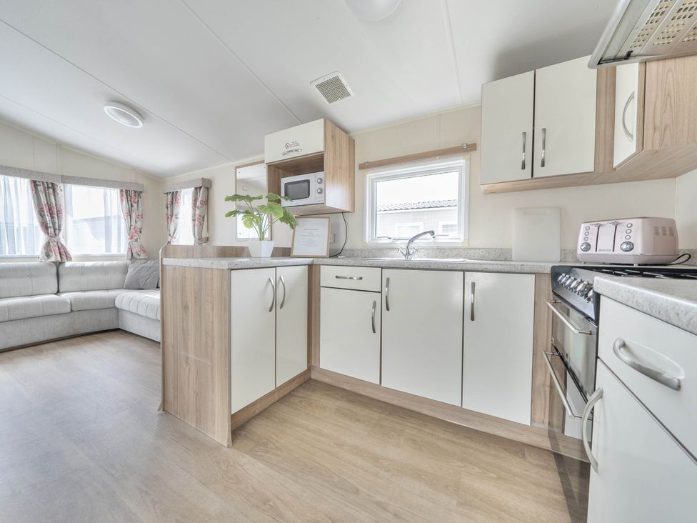 A kitchen with cabinets and a microwave at Mersea Beach Retreat in Colchester