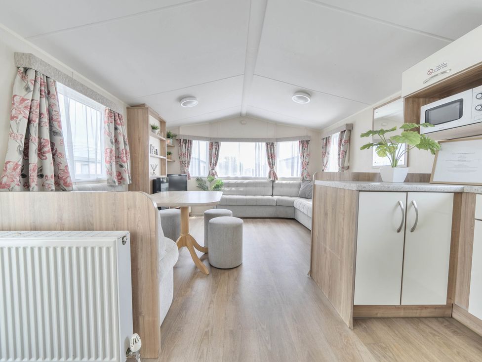 A living room with a sofa and table at Mersea Beach Retreat in Colchester
