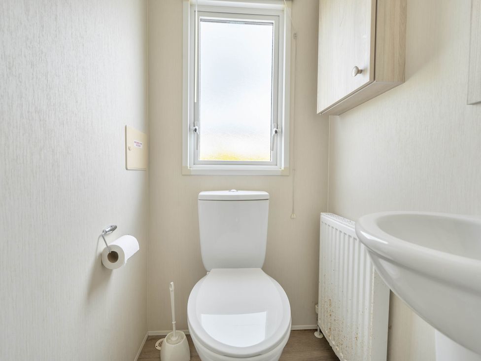A bathroom with a toilet and sink at Mersea Beach Retreat in Colchester