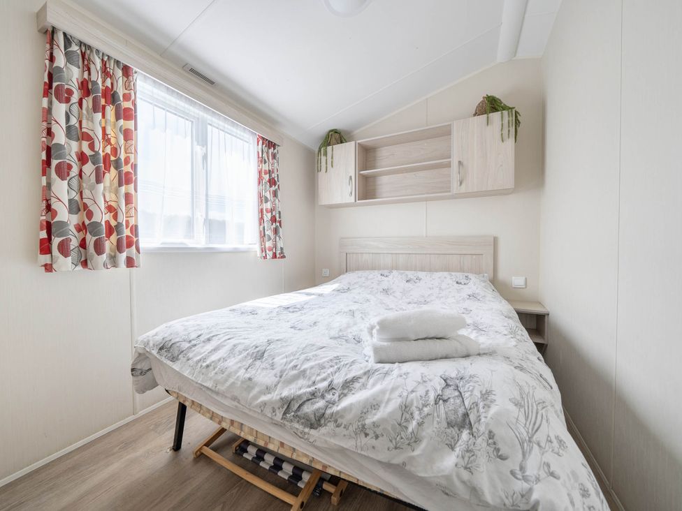 A bedroom with a bed and curtains at Mersea Beach Retreat in Colchester