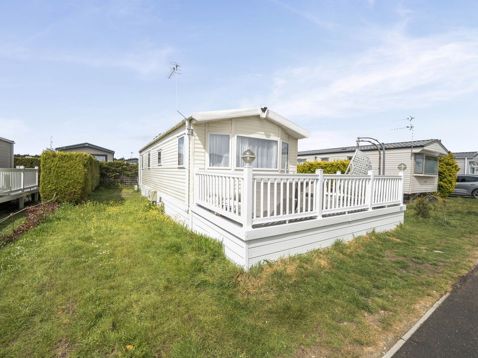 A mobile home with a deck and a hedge at Mersea Beach Retreat in Colchester