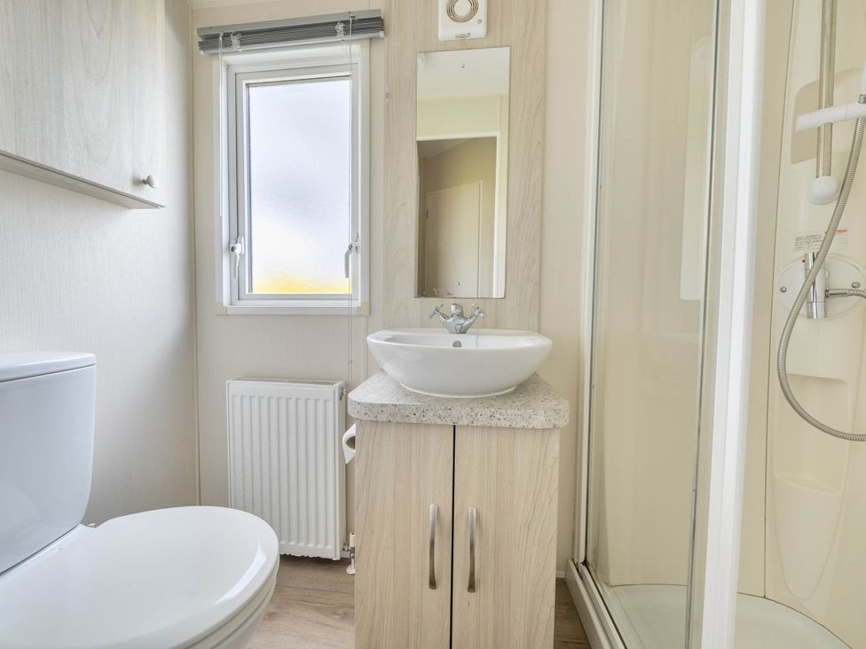 A bathroom with a sink, toilet and shower at Mersea Beach Retreat, Colchester