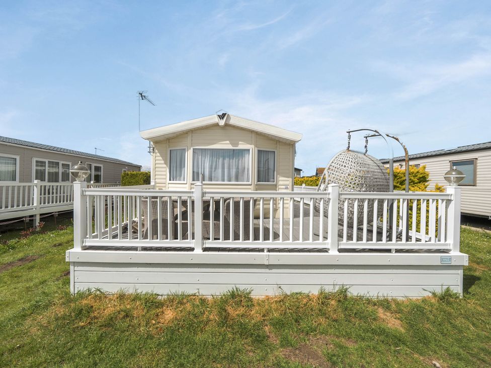 A mobile home with a deck and hanging chair at Mersea Beach Retreat in Colchester