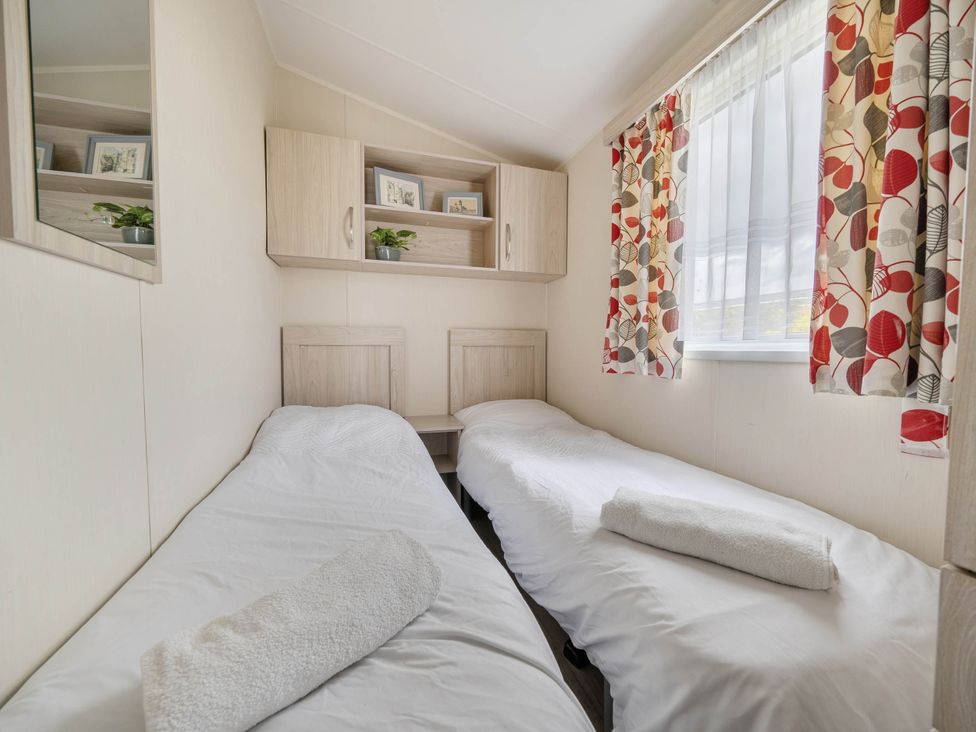 A bedroom with two single beds and shelves at Mersea Beach Retreat in Colchester