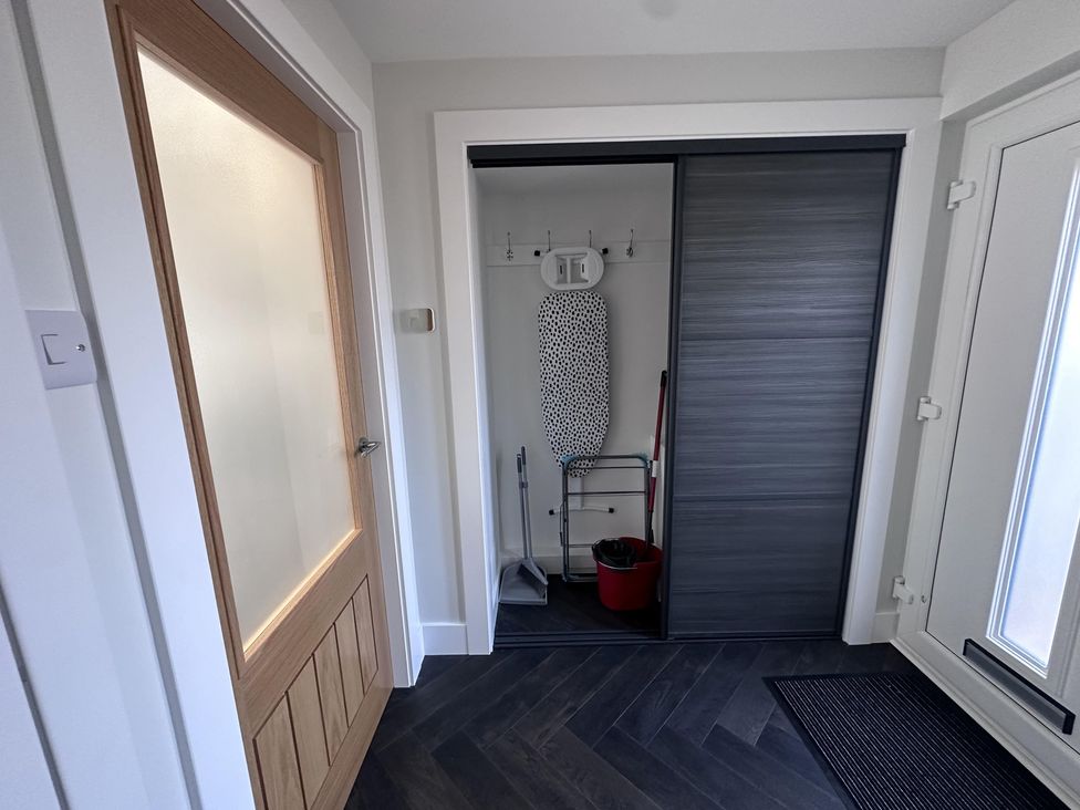 A hallway featuring a closet with an ironing board and cleaning supplies at 22 Fraser Avenue