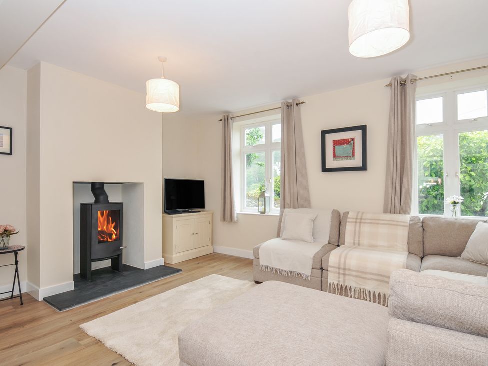 A living room with a fireplace and television at Barton House in Looe