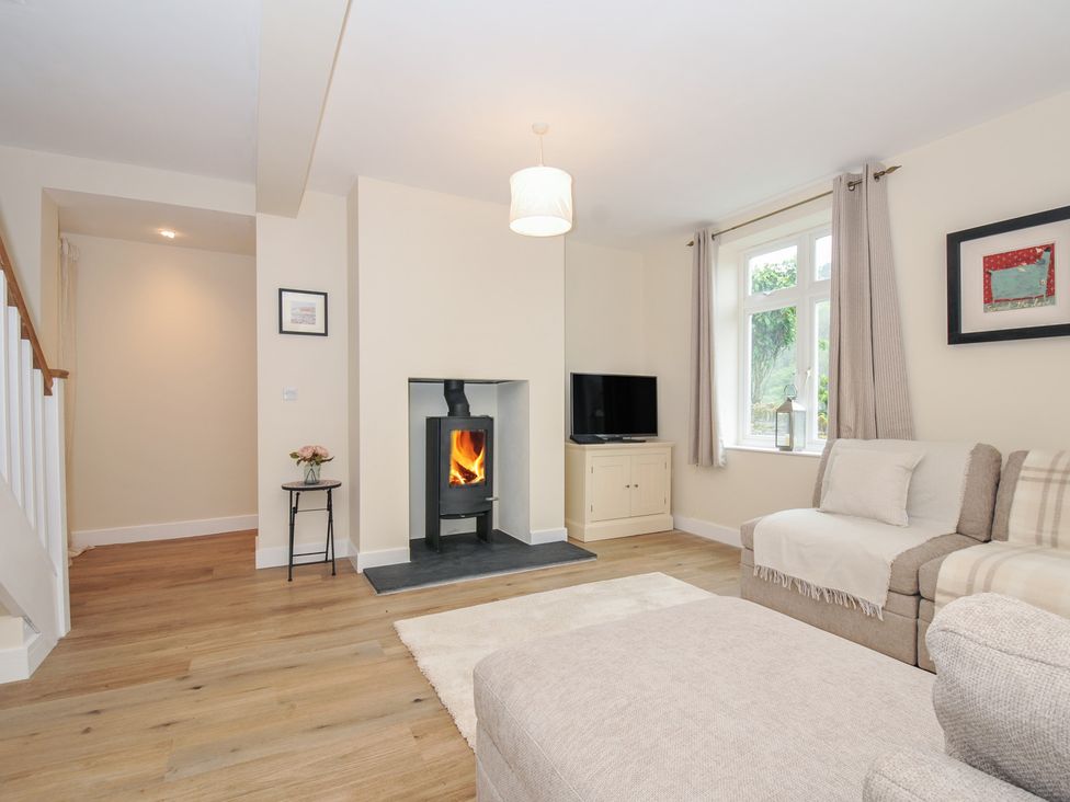 A living room with a fireplace and television at Barton House in Looe