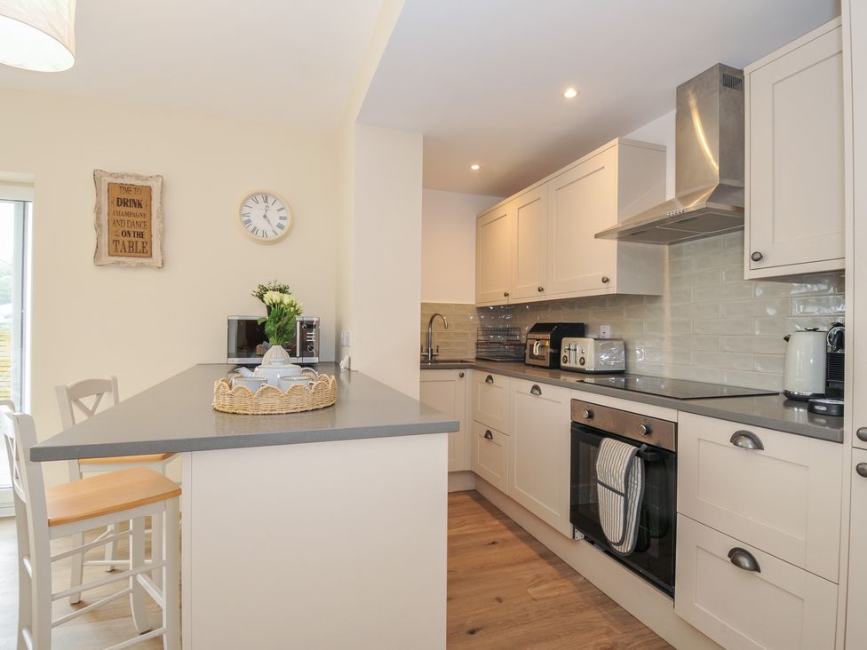 A kitchen with a bar stool, oven, and sink at Barton House in Looe