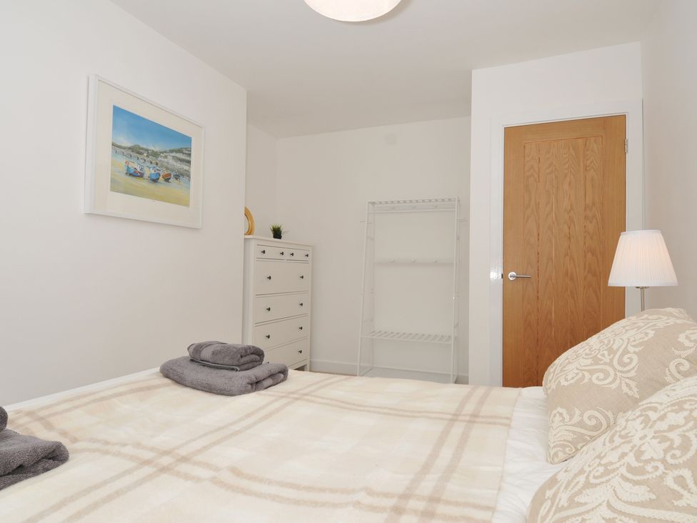 A bedroom with a bed and dresser at Barton House in Looe
