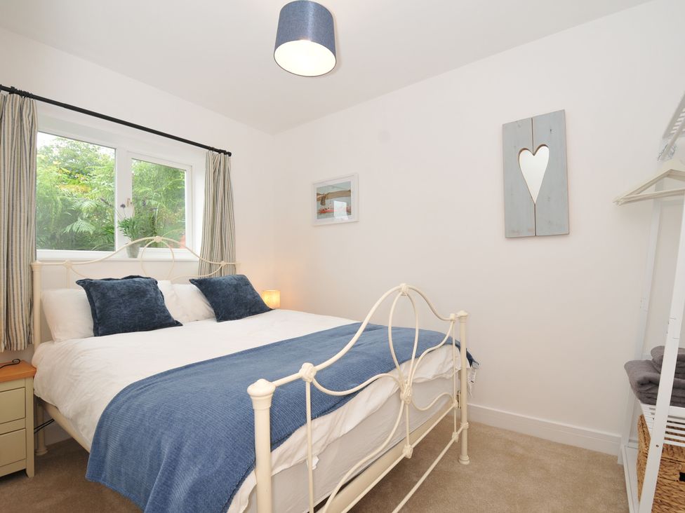 A bedroom with a bed and window at Barton House in Looe