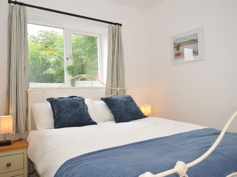 A bedroom with a bed and window at Barton House in Looe