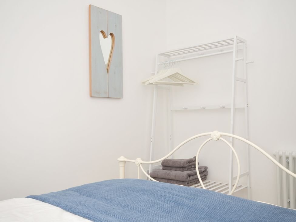 A bedroom with a bed and a clothes rack at Barton House in Looe