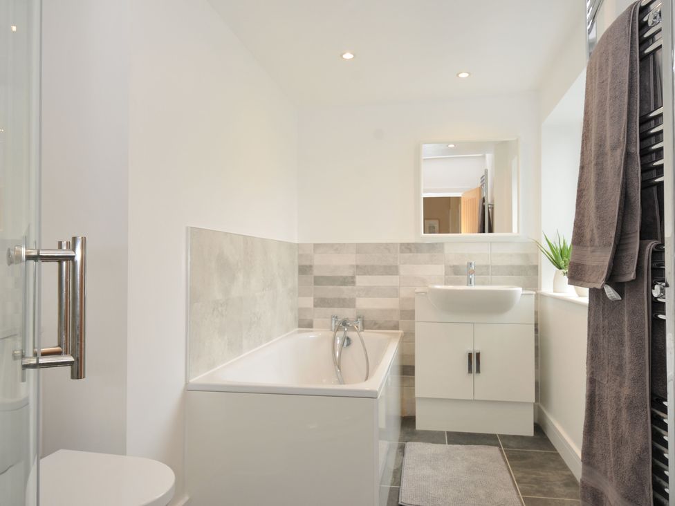 A bathroom with a bathtub, sink and shower at Barton House in Looe