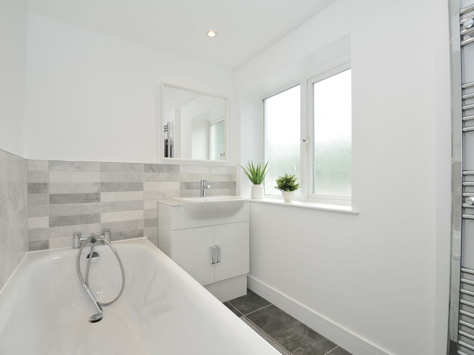 A bathroom featuring a bathtub, sink, and windows at Barton House in Looe