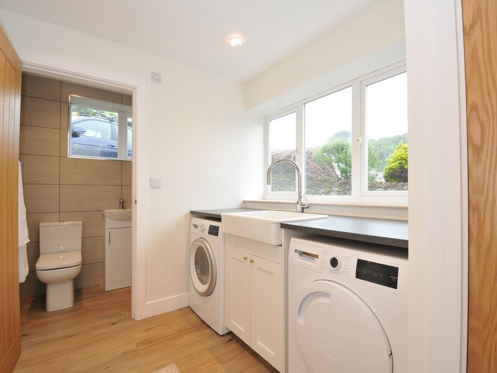 A laundry room with appliances and a window at Barton House in Looe
