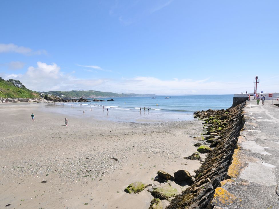 A beach with people walking near the water at Barton House in Looe