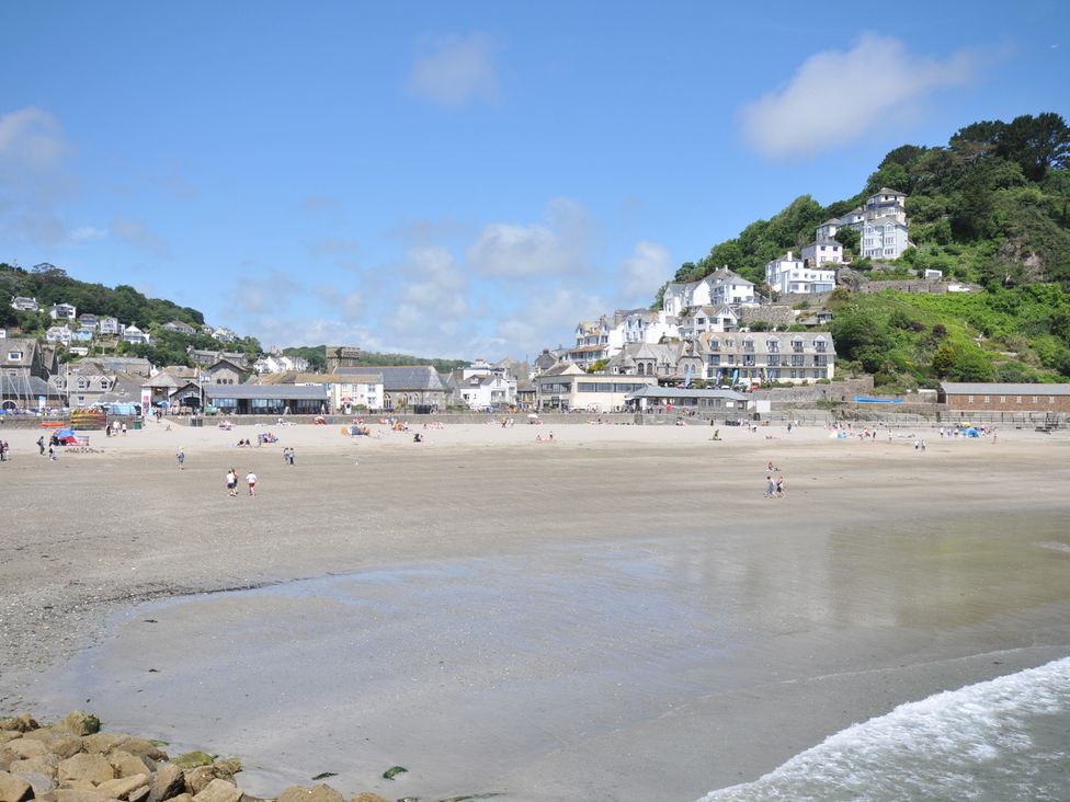 A beach with people and buildings on the shore at Barton House Looe