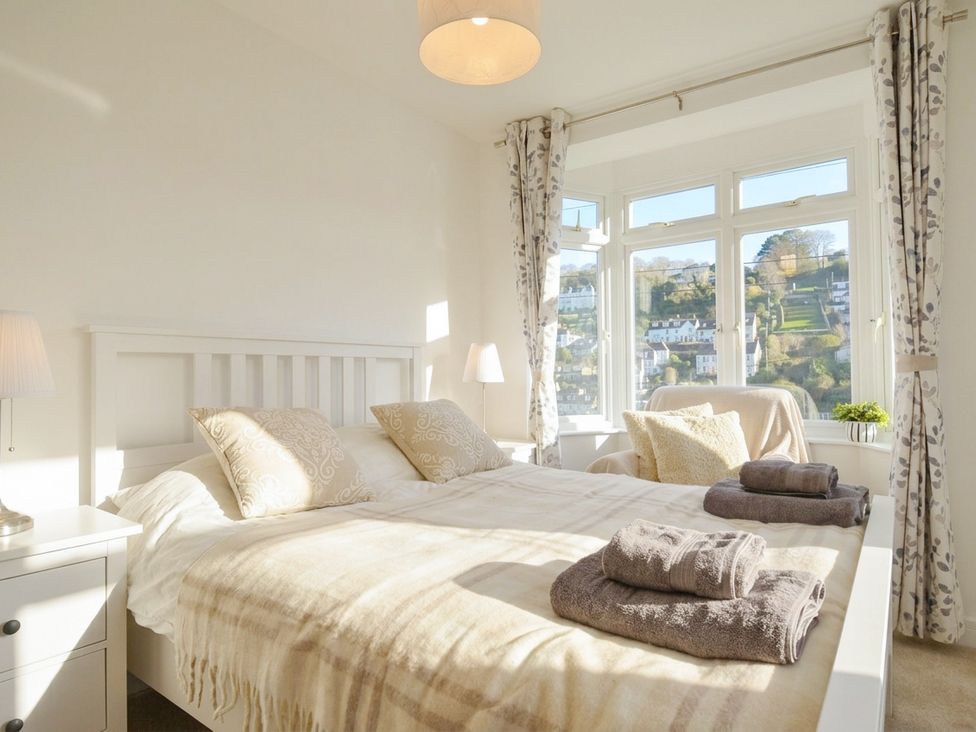 A bedroom with a bed and window at Barton House in Looe