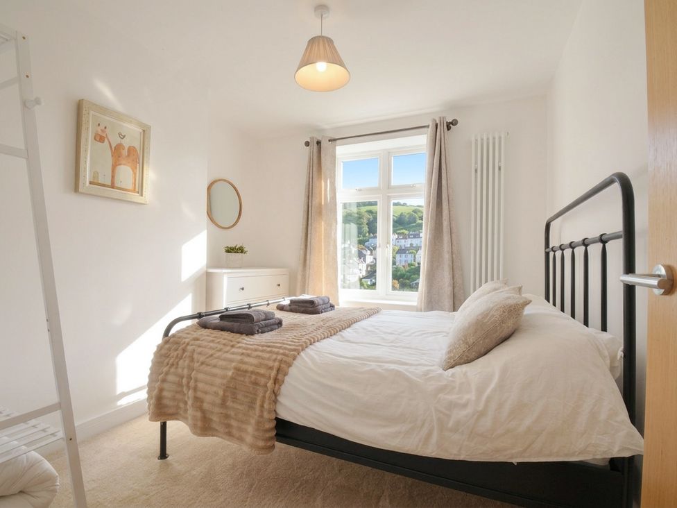 A bedroom with a bed and window at Barton House in Looe