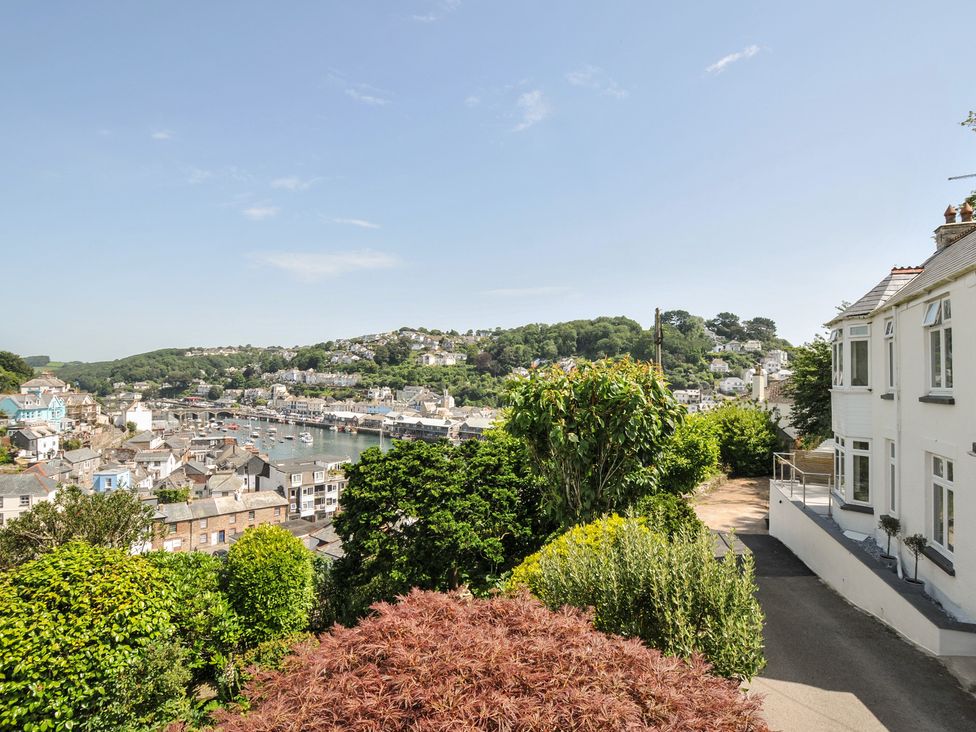 A view of a harbor from a house with trees and bushes at Barton House in Looe