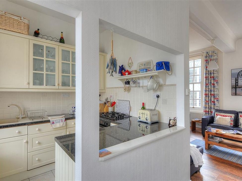 A kitchen with appliances and a view of the living area at 1 The Old Posthouse Lyme Regis