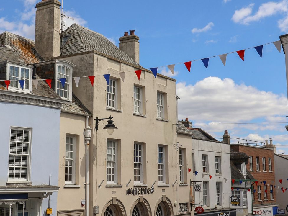 A street view featuring buildings and bunting at 1 The Old Posthouse in Lyme Regis