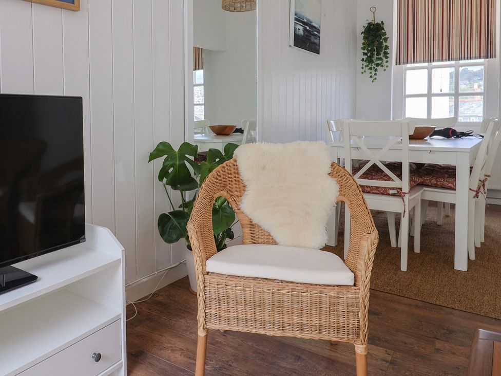 A living room with a television and a rattan chair at 1 The Old Posthouse in Lyme Regis