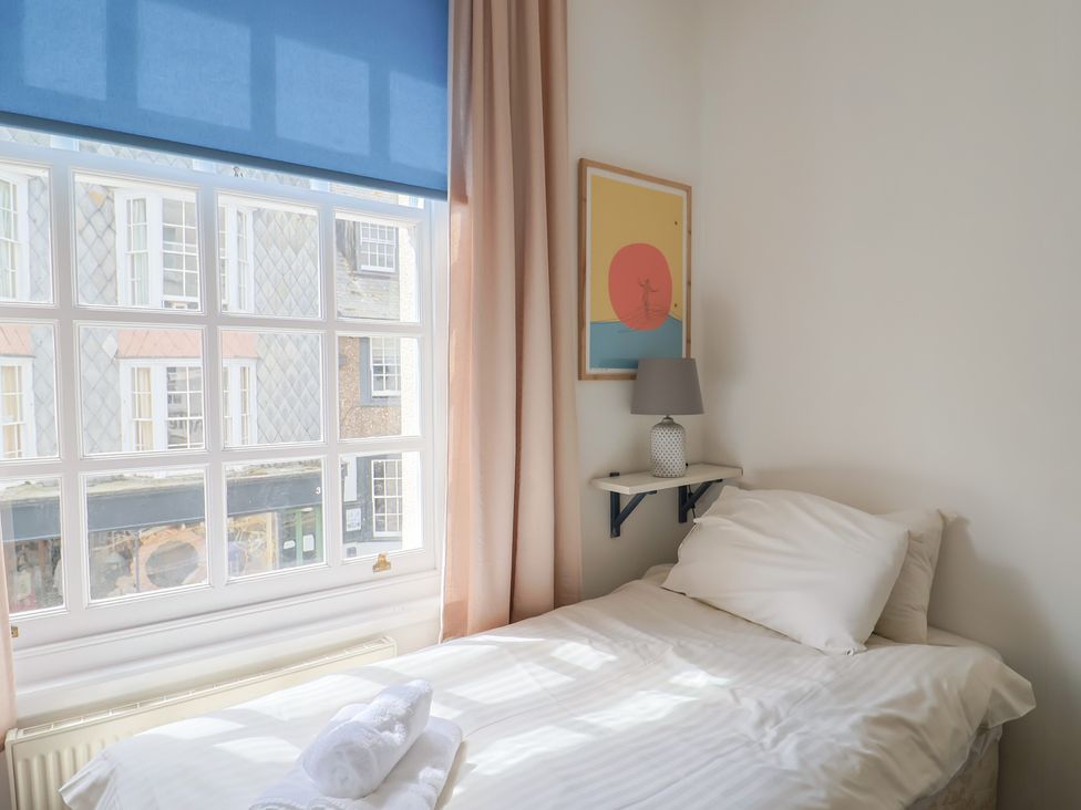 A bedroom with a bed, lamp, artwork and window at 1 The Old Posthouse in Lyme Regis