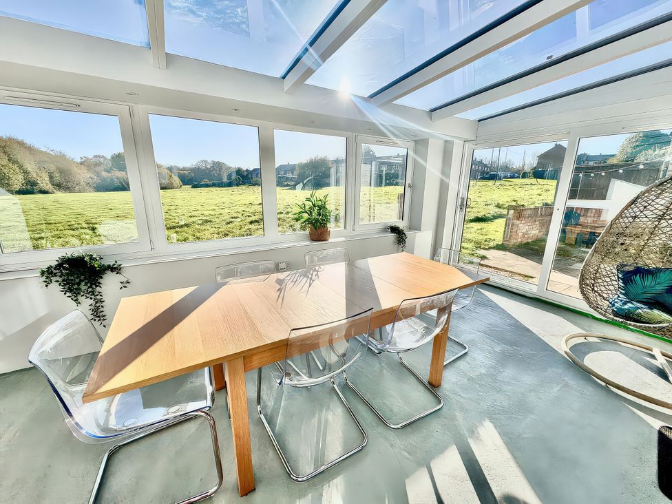 A conservatory with a dining table and transparent chairs at 10 Solent View Southampton