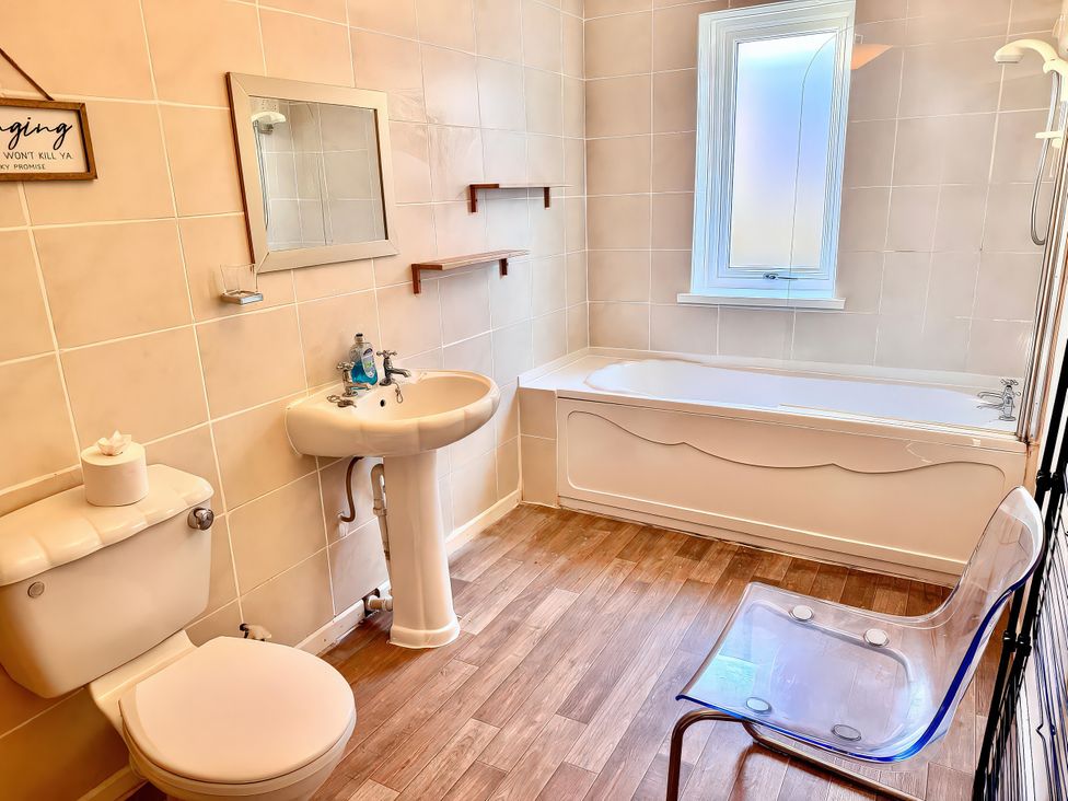 A bathroom with a sink, toilet, bathtub, and a mirror at 10 Solent View Southampton