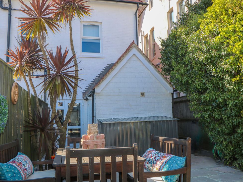 A garden with palm trees and a patio table at The Beach House