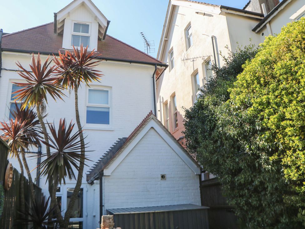 An outdoor view of a house with palm trees and bushes at The Beach House in 