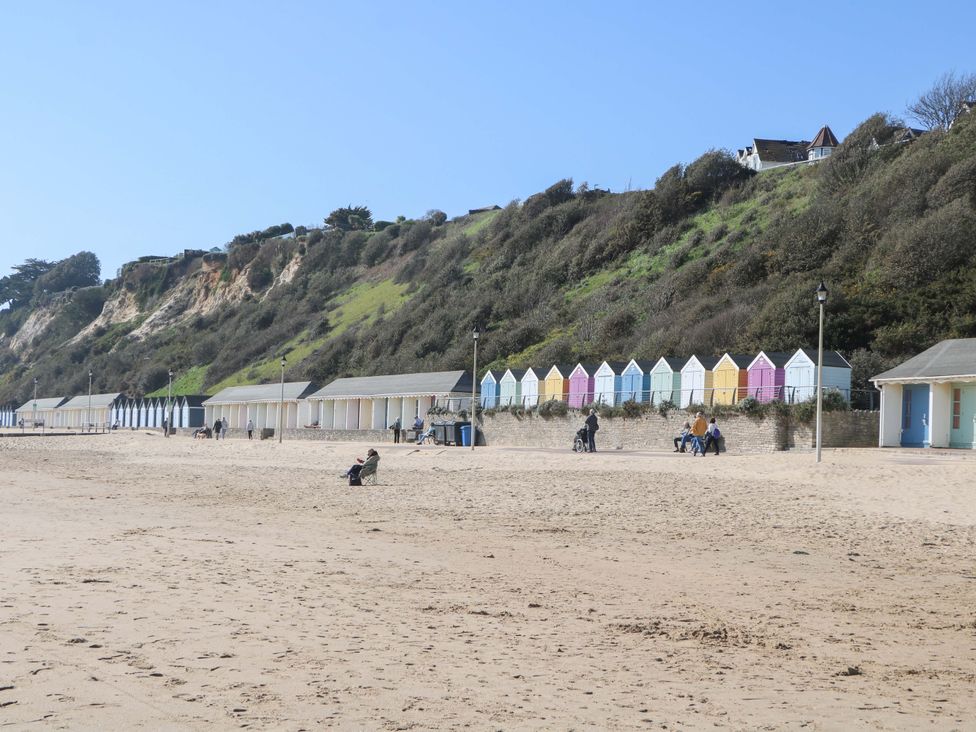 A beach with colorful beach huts and people enjoying the day at The Beach House in 
