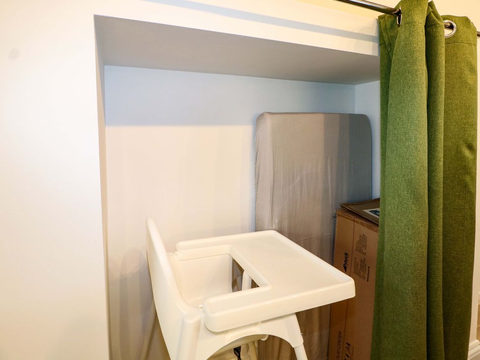 A high chair next to a mattress and cardboard box in a storage area at The Beach House in Bournemouth