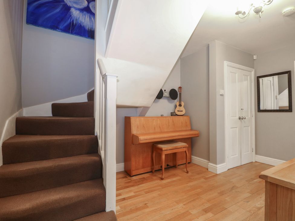 A hallway with staircase and piano at Tiffanys Coach House in Bournemouth