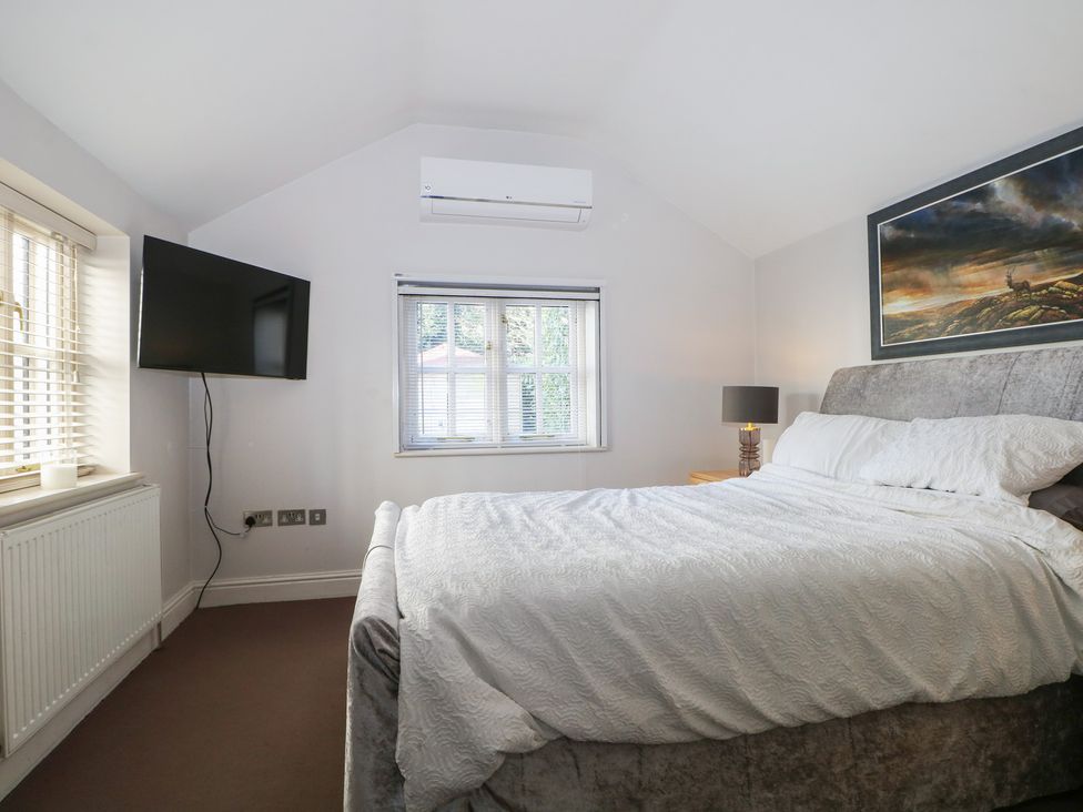 A bedroom with a bed and a television at Tiffanys Coach House in Bournemouth
