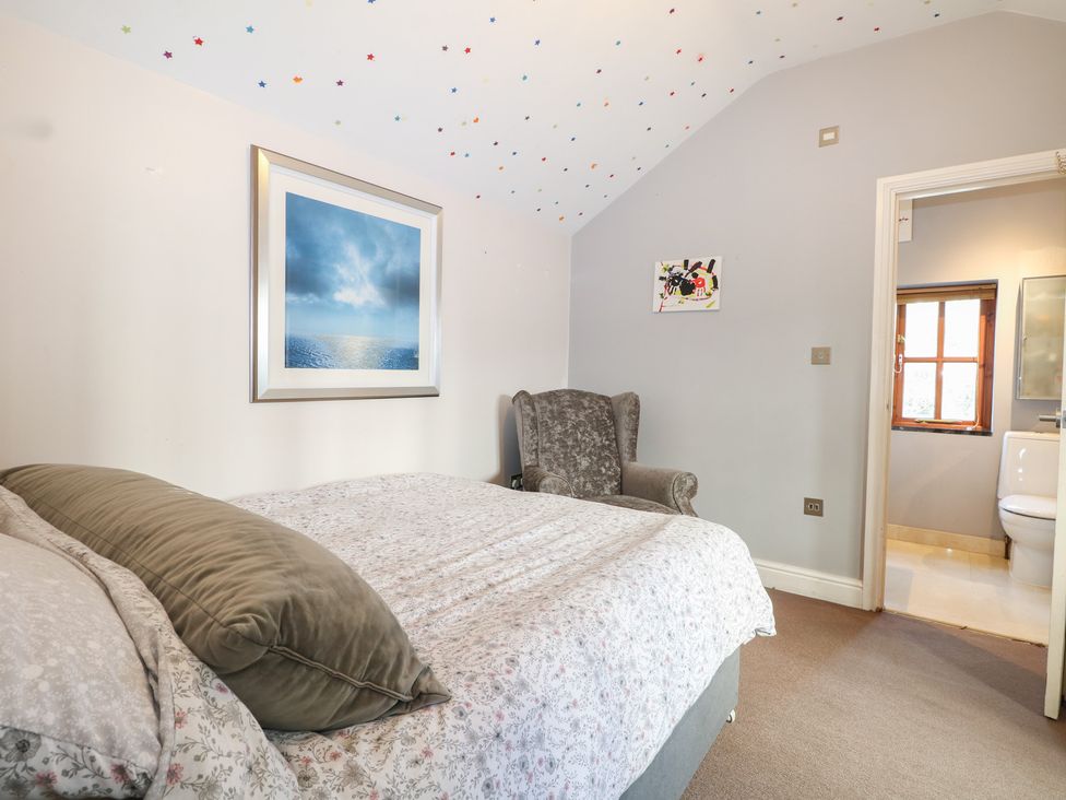 A bedroom with a bed and an armchair at Tiffanys Coach House in Bournemouth