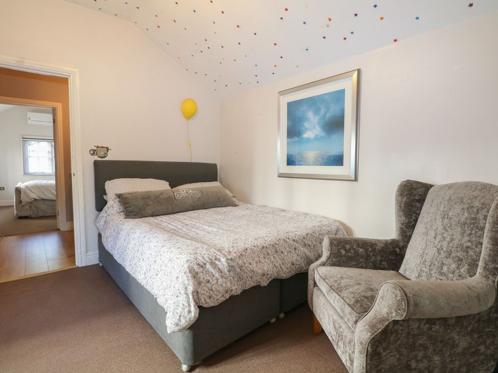 A bedroom with a bed and a chair at Tiffanys Coach House in Bournemouth